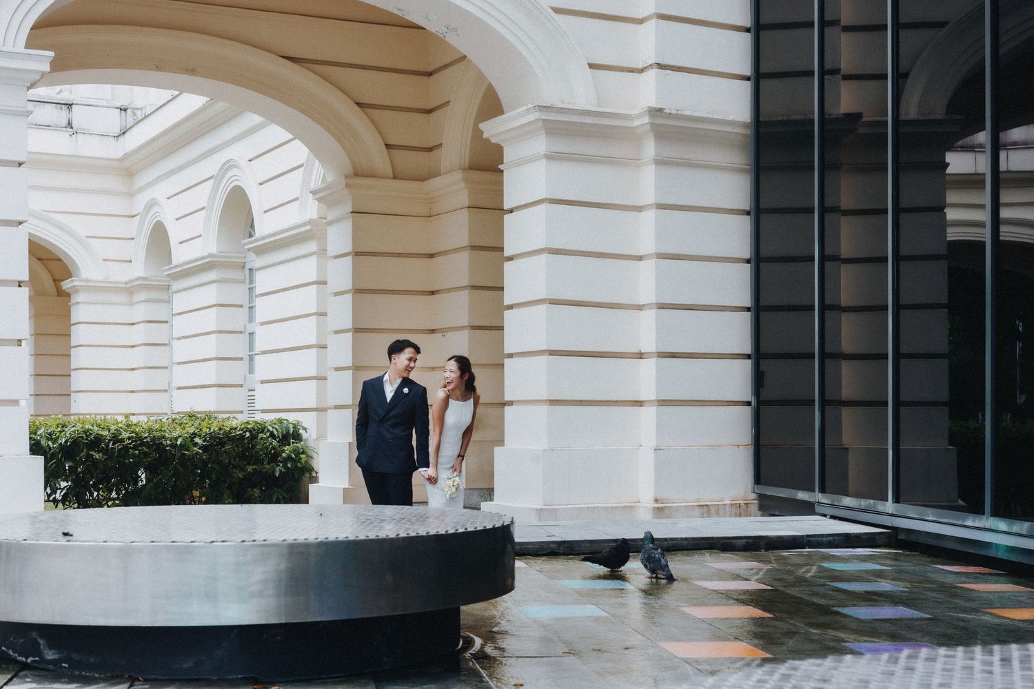 Modern white colonnade architecture with arched columns and glass windows in a luxury building exterior.