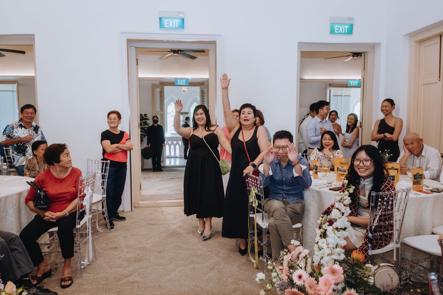 Guests celebrating at an elegant indoor wedding reception with floral arrangements and festive atmosphere.