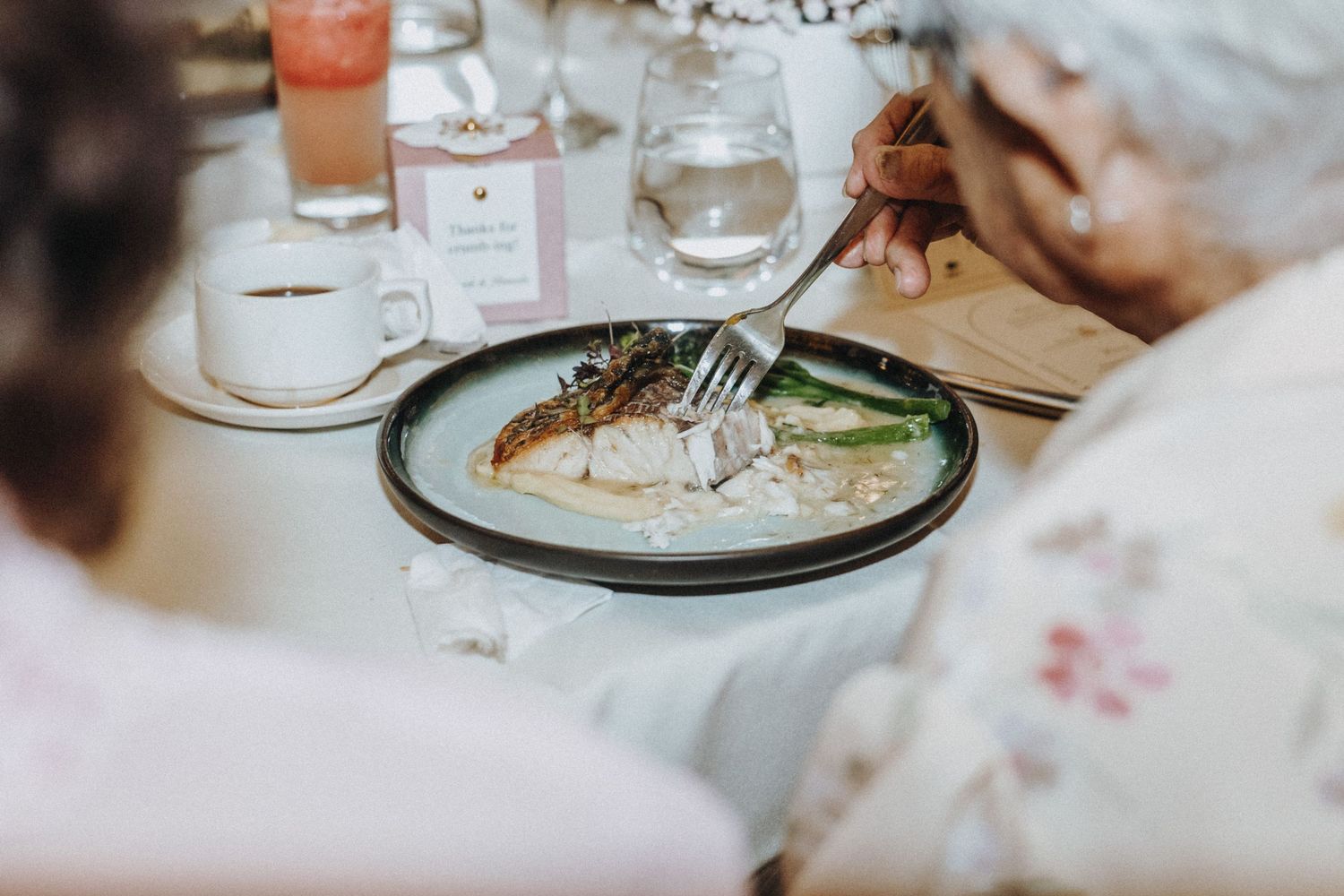 Close-up of a plated fish dish being eaten at an elegant wedding reception dinner.