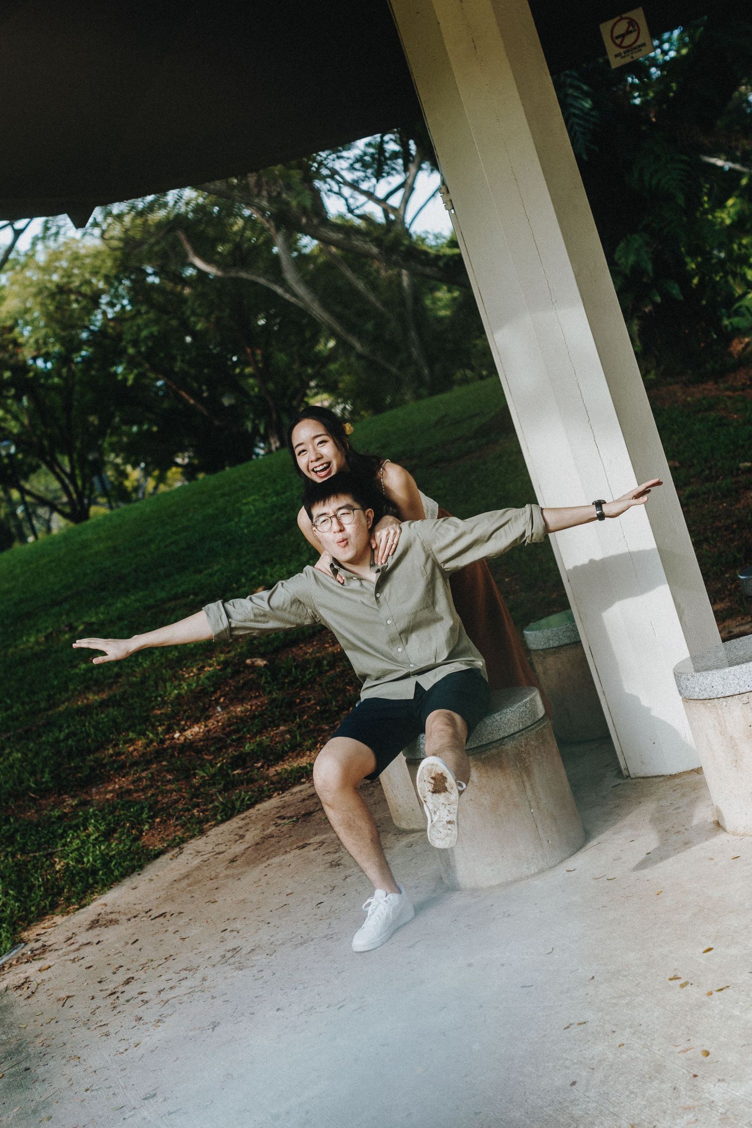 A playful scene at a white pillar structure with two people posing together outdoors.