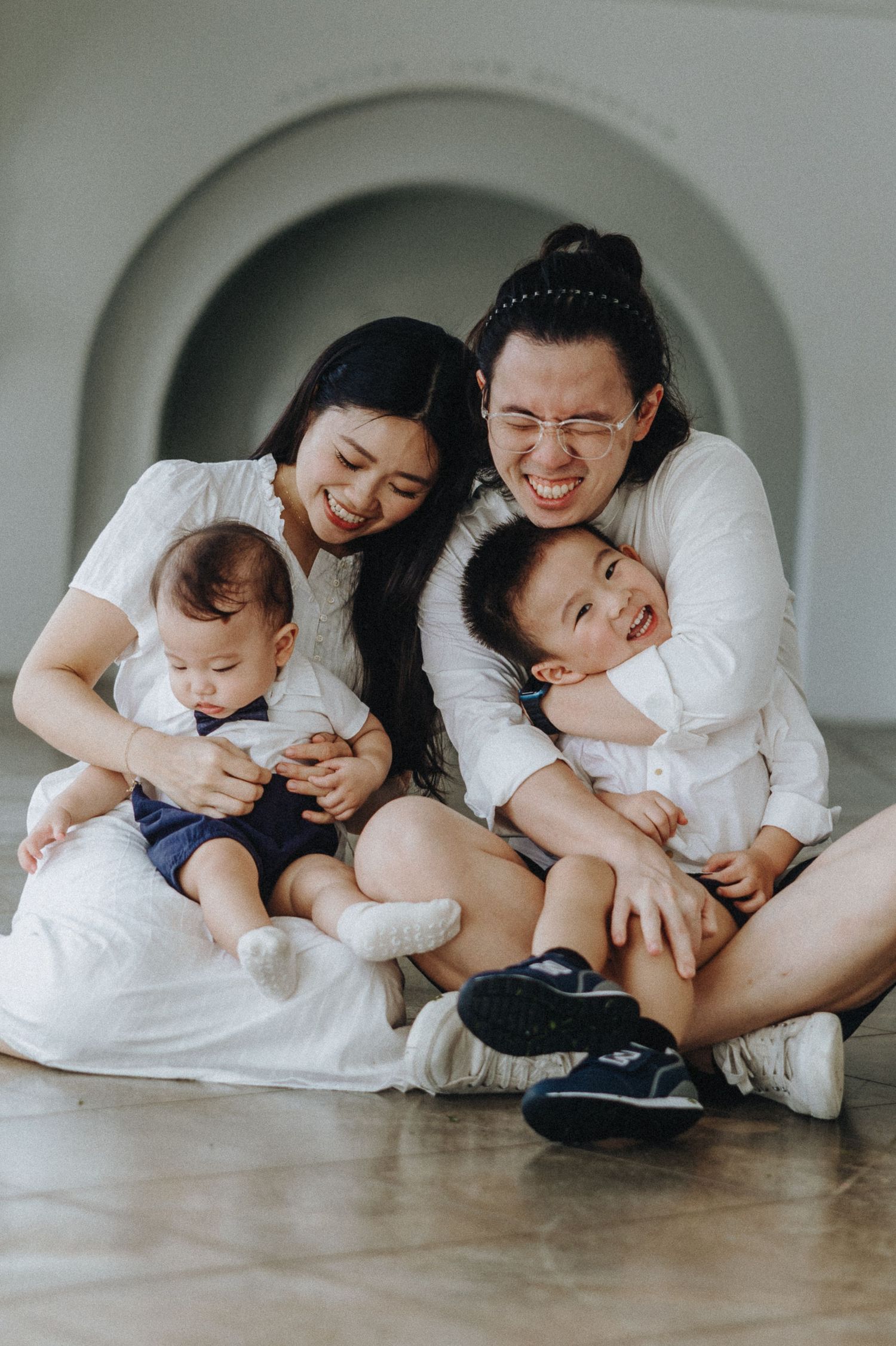 A joyful family sharing a tender moment together while sitting on the floor in a bright hallway.