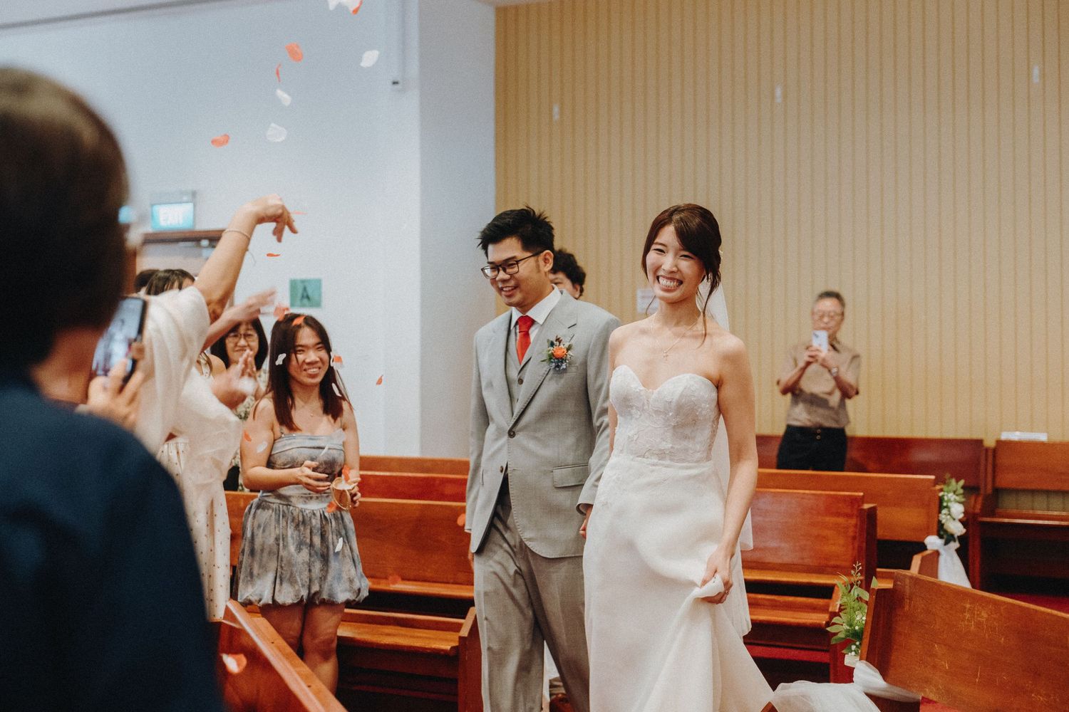 Wedding ceremony celebration with guests tossing flower petals in a church.