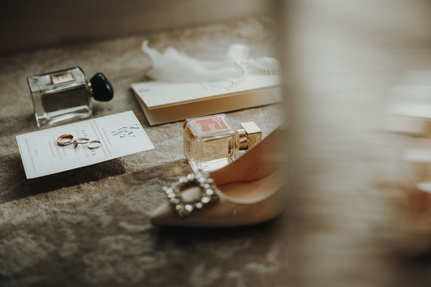 Wedding photography setup showing rings, invitations, and other details on a wooden surface.