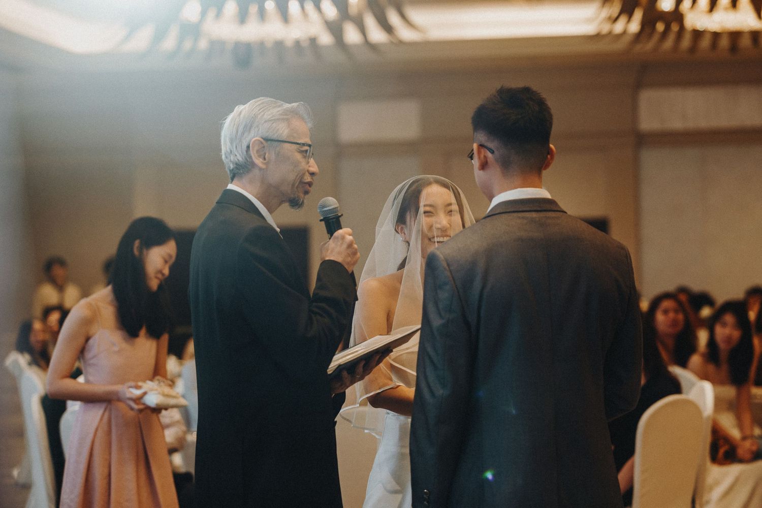 An intimate wedding ceremony moment with an officiant in a hotel ballroom.