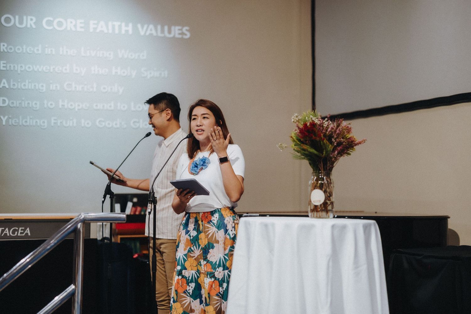 Two people stand at a podium presenting core faith values during a church service.