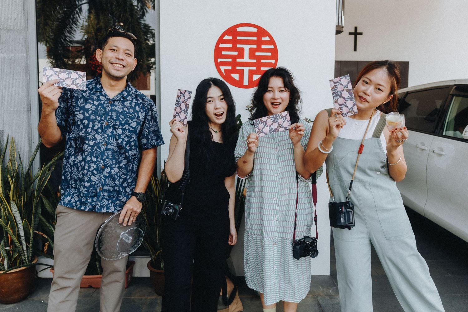 Group of friends in casual outfits posing together against a wall with a red circular symbol.