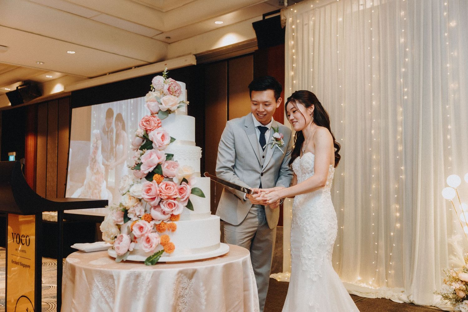 Wedding couple cutting their elegant floral wedding cake at their reception.
