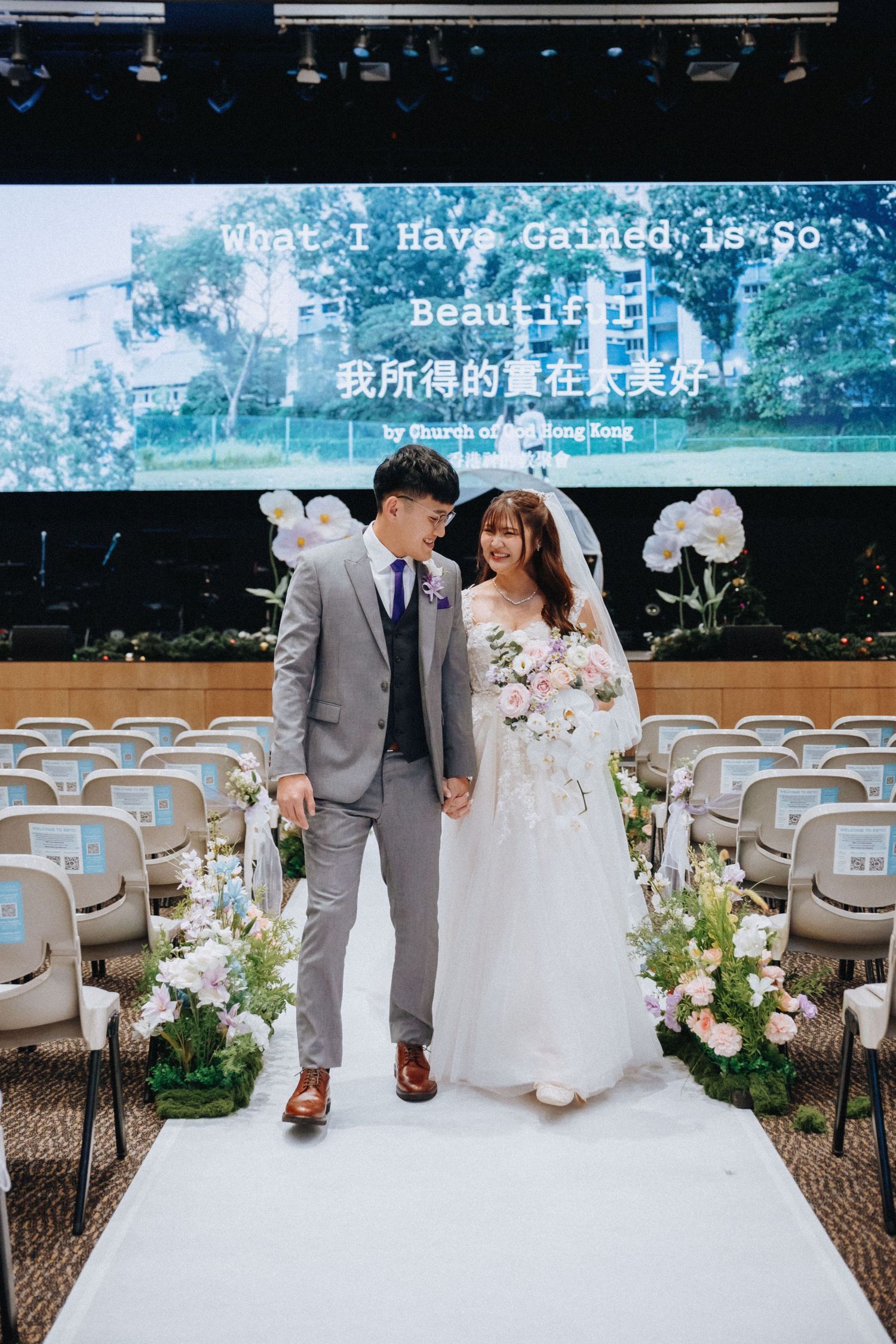 Elegant wedding ceremony setup with white chairs and floral decorations in an outdoor garden venue.