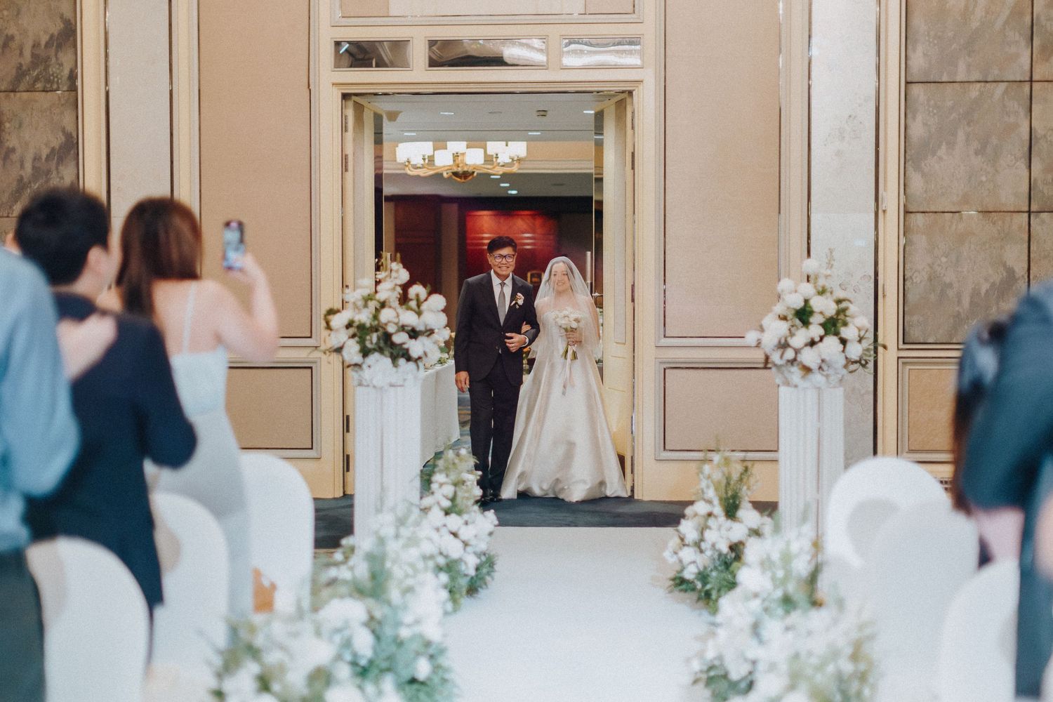 Elegant wedding venue decorated with white floral arrangements and marble columns.