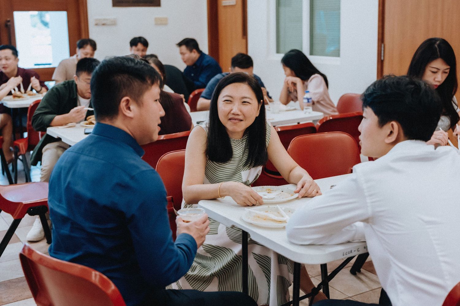 Wedding guests laugh and converse at round tables during a casual reception gathering.