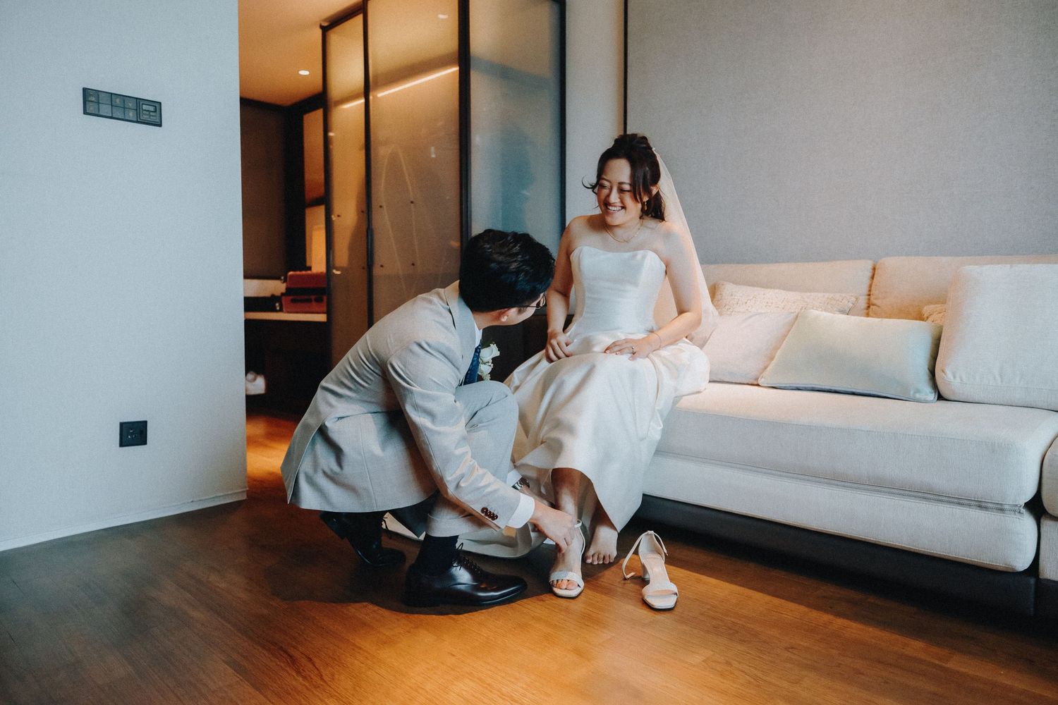 Wedding party lounging casually on white furniture in a modern minimalist room.