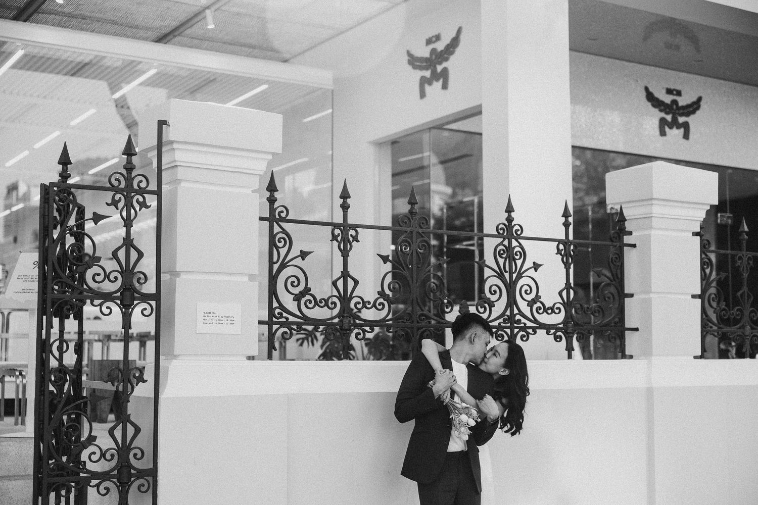Ornate decorative iron railings and vertical posts in a black and white interior space with white columns and walls.