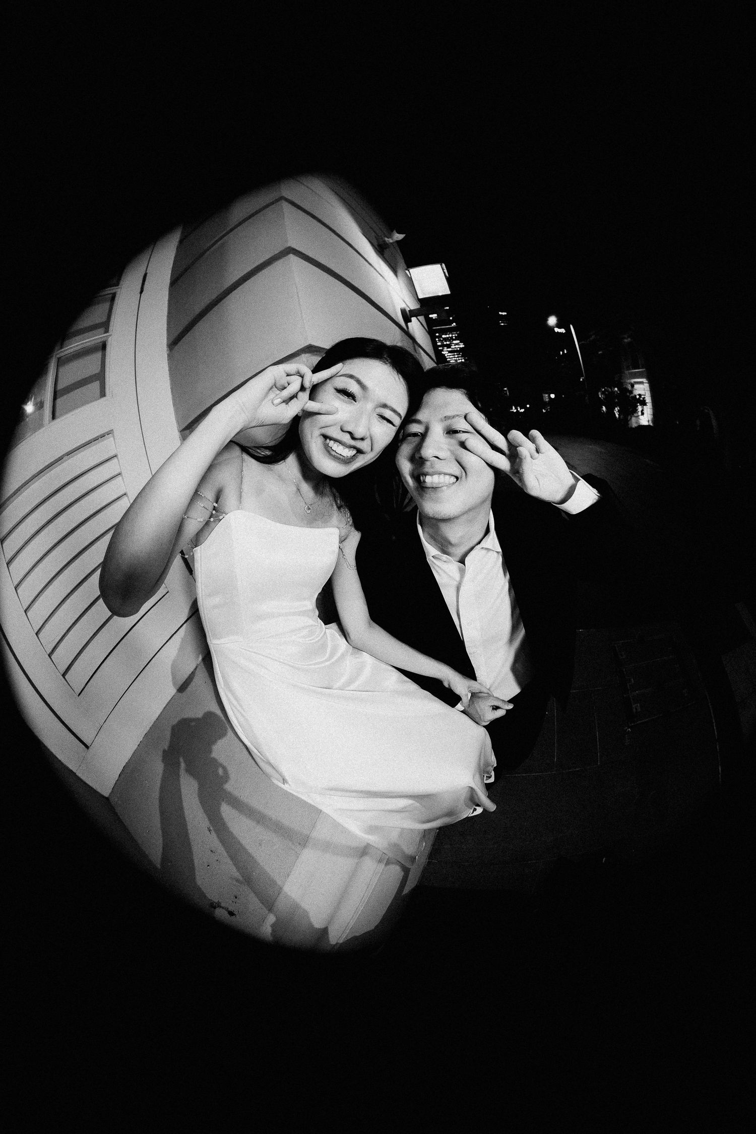 A black and white fisheye shot captures a playful wedding moment with creative composition.