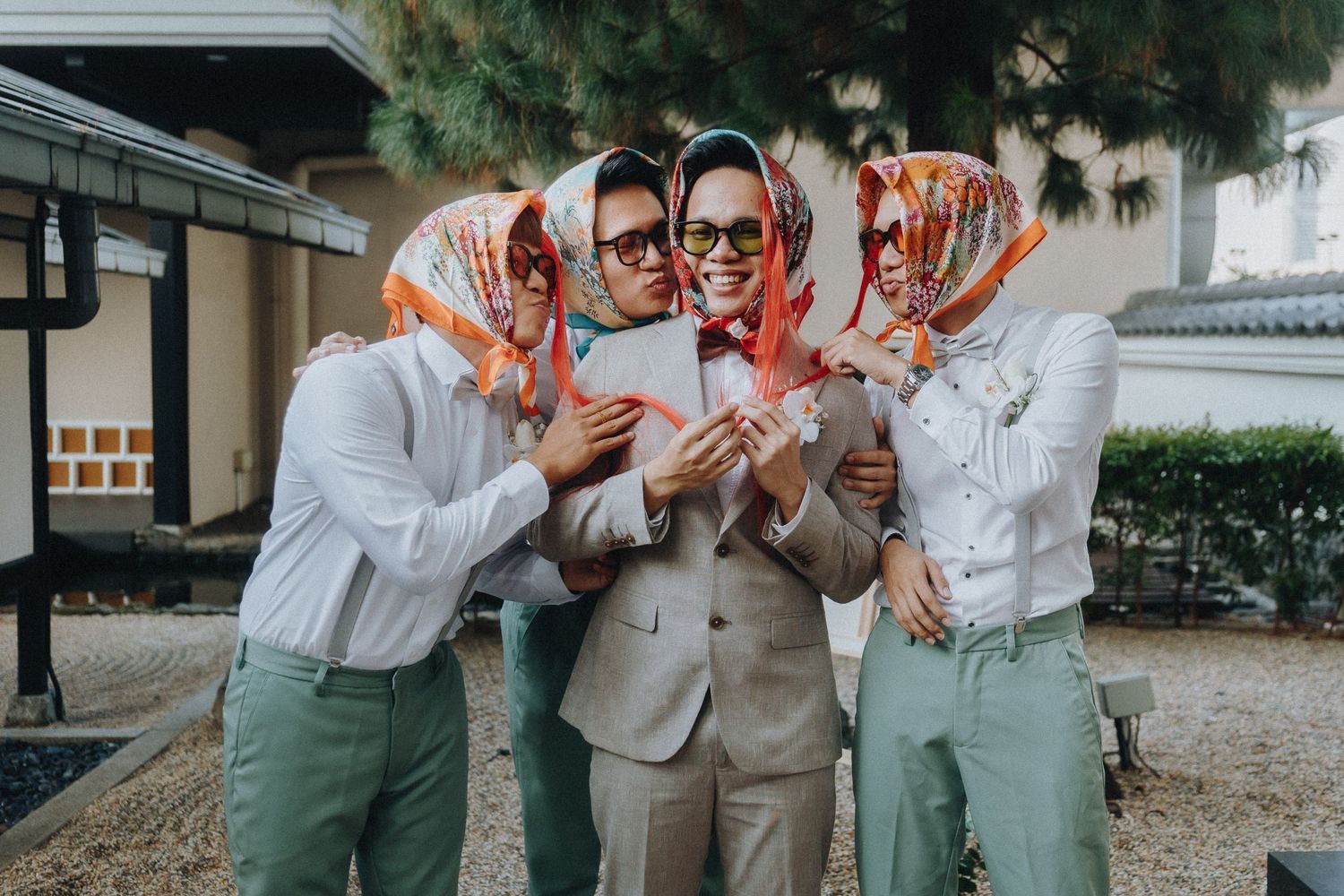 A group in coordinated outfits and headscarves gather closely together outdoors near traditional architecture.