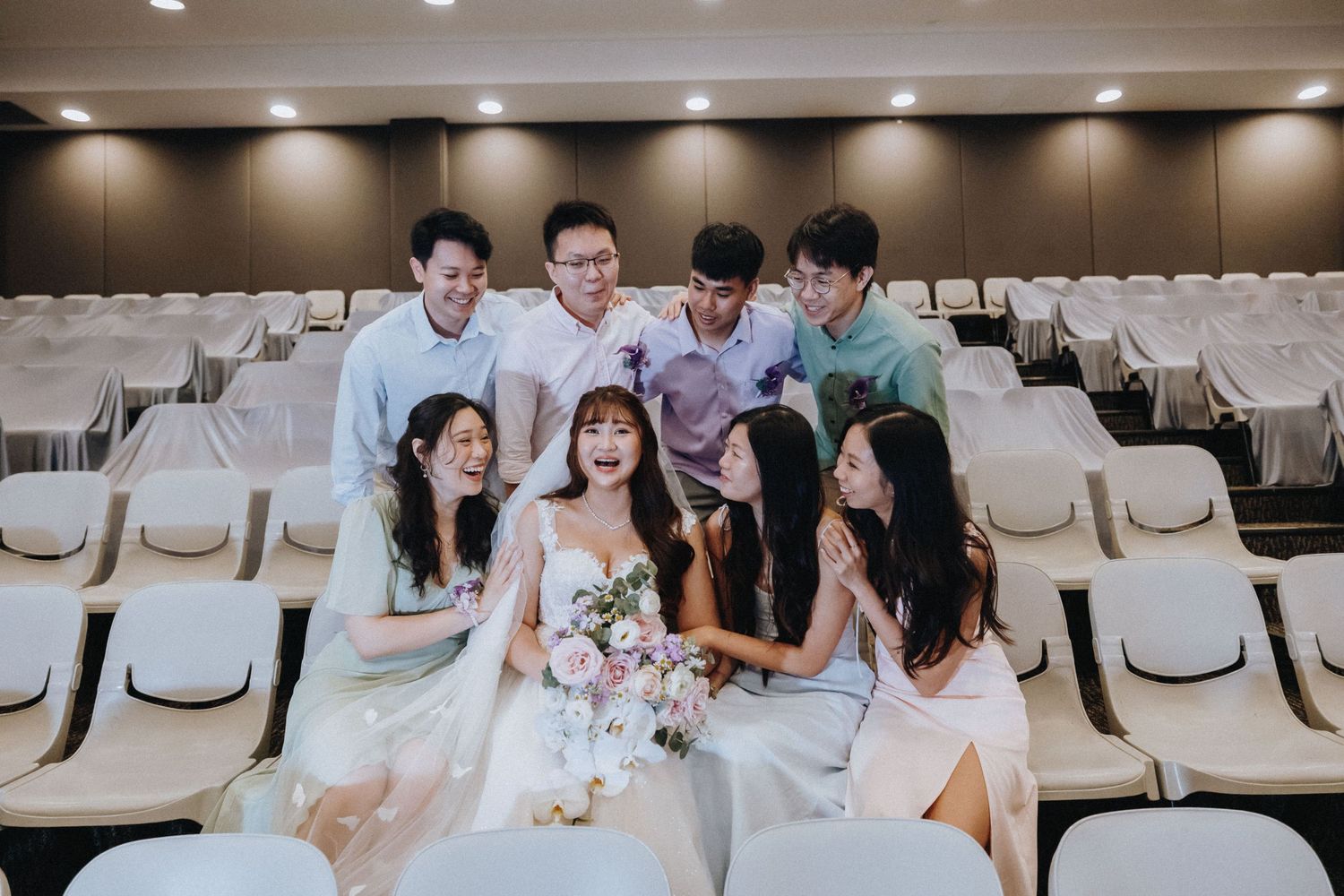 Indoor wedding venue with rows of white chairs and elegant lighting in an auditorium setting.