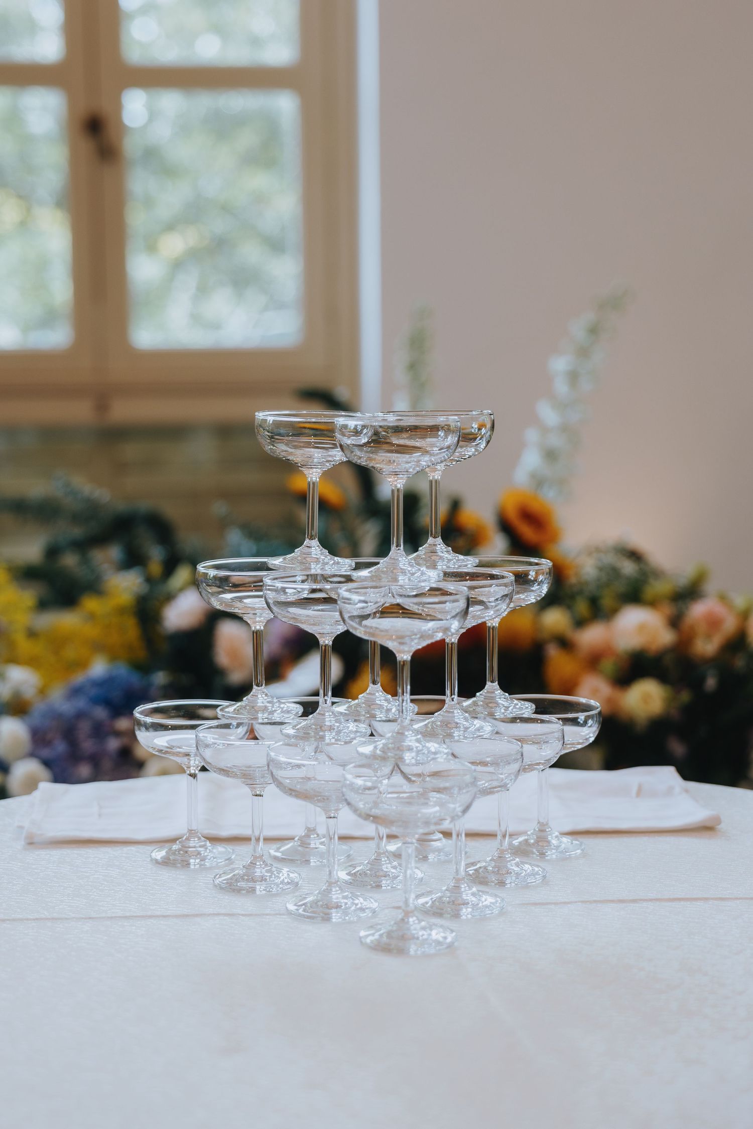 Elegant pyramid of champagne glasses arranged on a white tablecloth at a wedding reception.