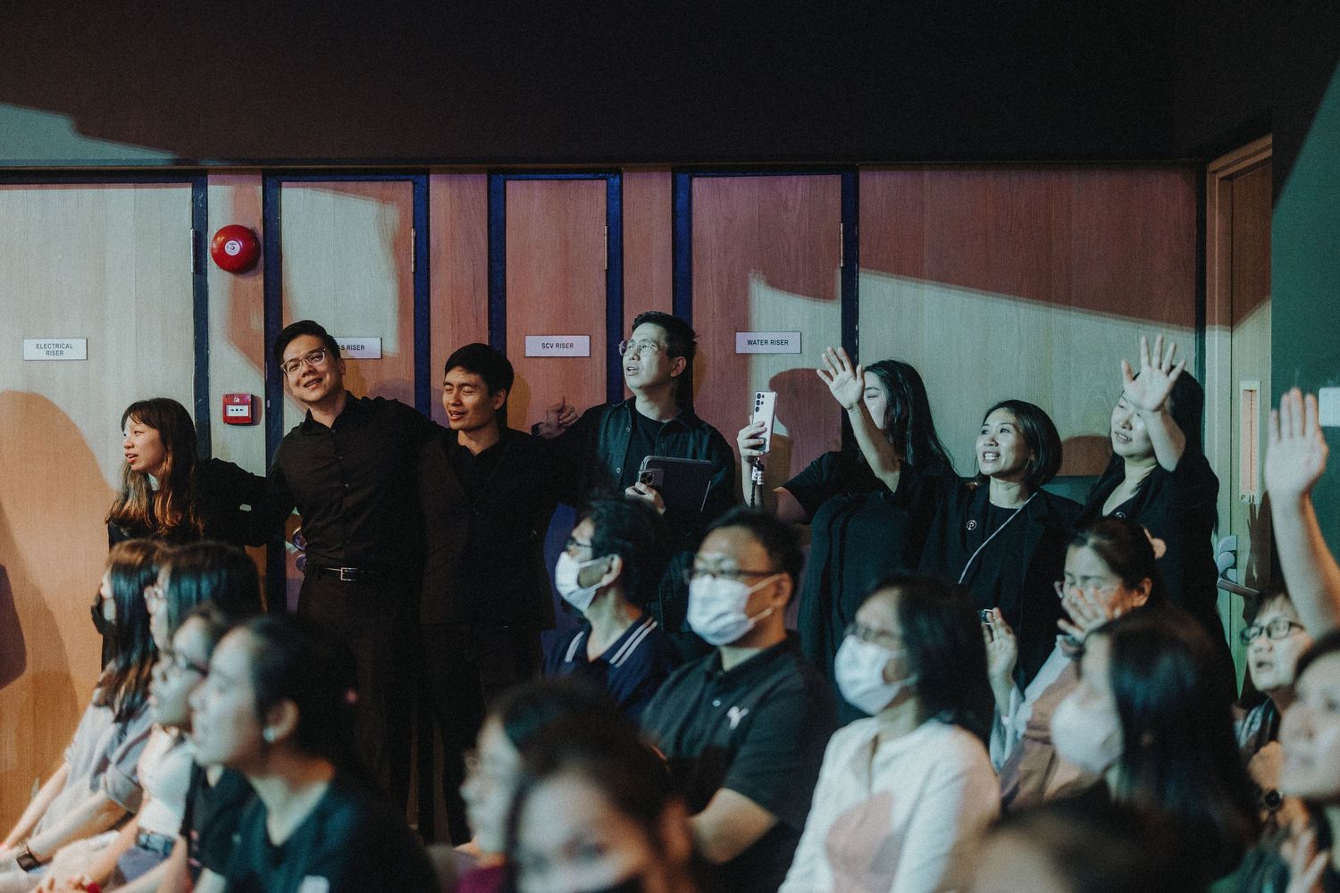 A congregation stands in worship during a dimly lit church service.