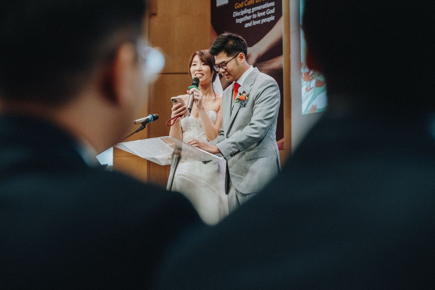 Intimate moment captured during wedding ceremony through silhouetted observers.