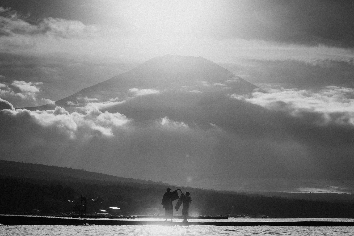 Dramatic black and white landscape with mountains silhouetted against cloudy sky.