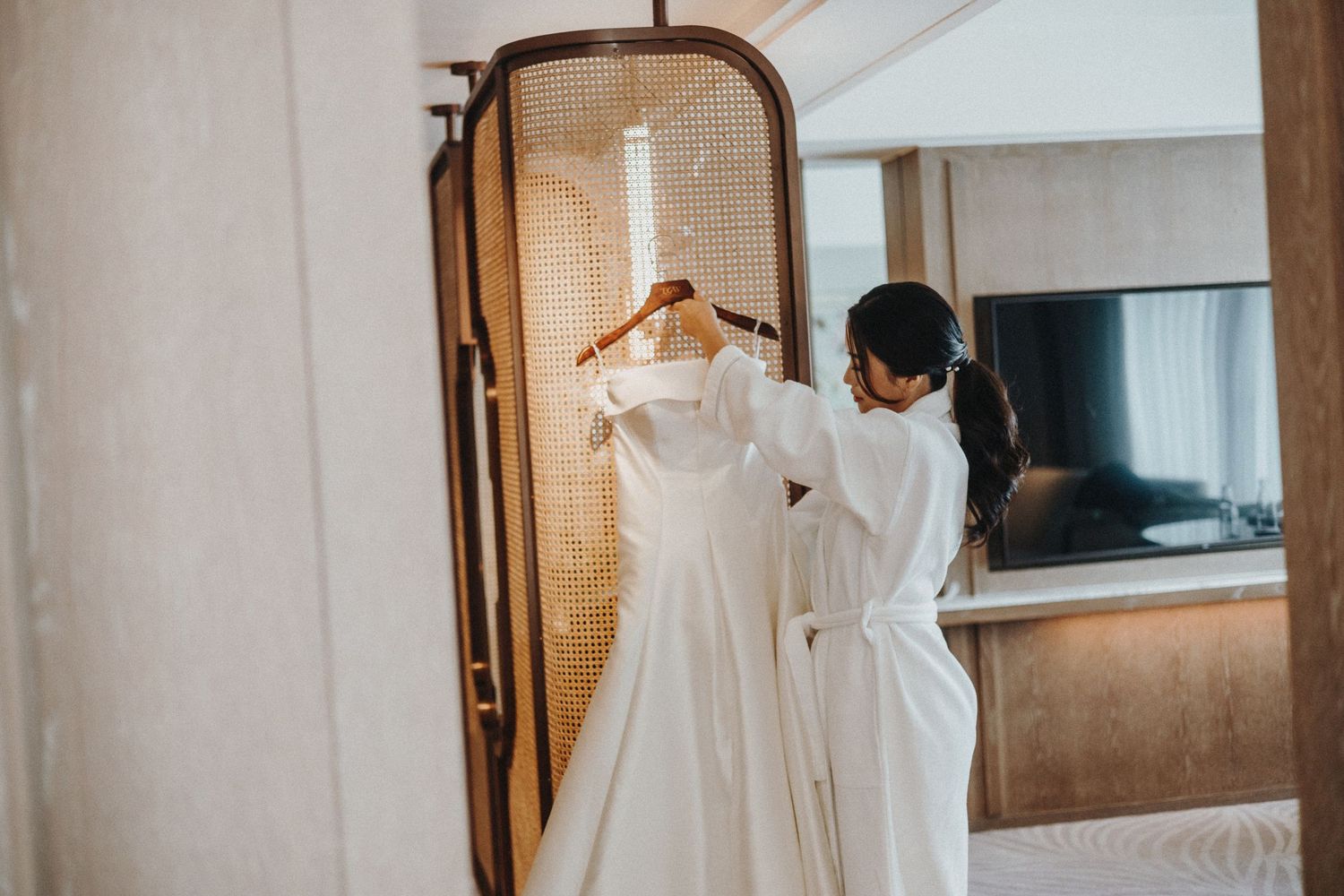 Elegant white wedding dresses hanging on display in a sunlit room.