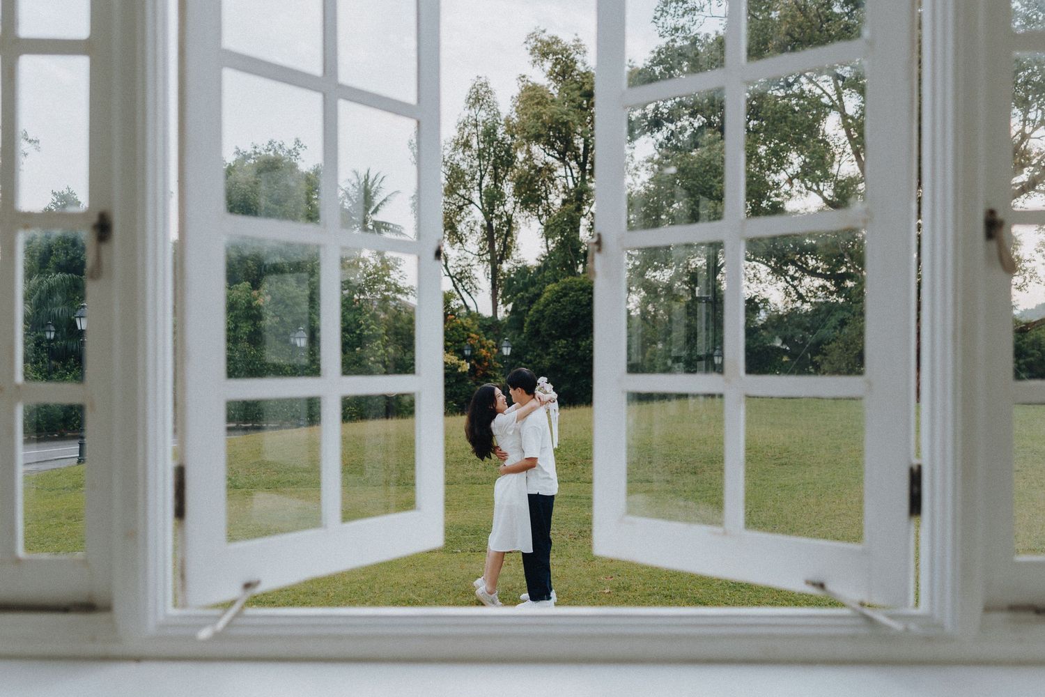 A series of white French doors open to a beautiful green lawn creating a bright, airy indoor-outdoor connection.