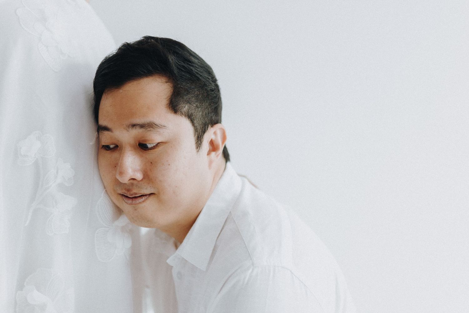 Asian couple in minimalist white studio setting posing closely for romantic portraits.