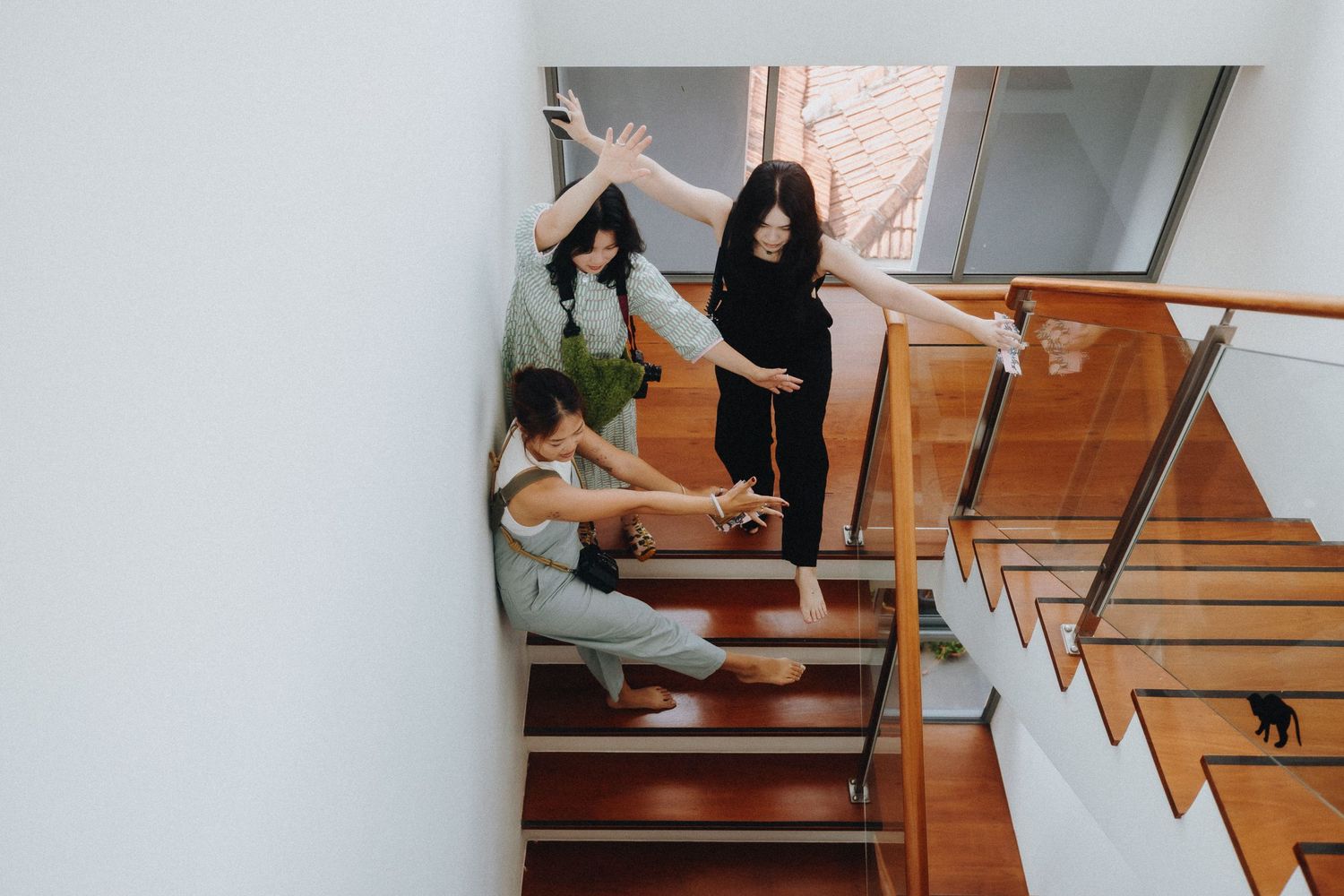 Two dancers practicing choreography on wooden stairs with handrails in a building.
