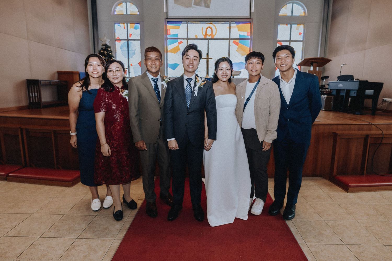 Newlyweds pose with wedding party guests in front of church altar.