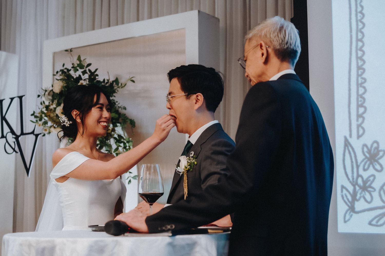 A couple dances during their first dance at an elegant white-decorated wedding reception ballroom.
