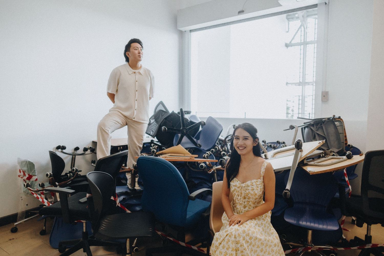 A couple poses playfully in casual attire against a white studio background.