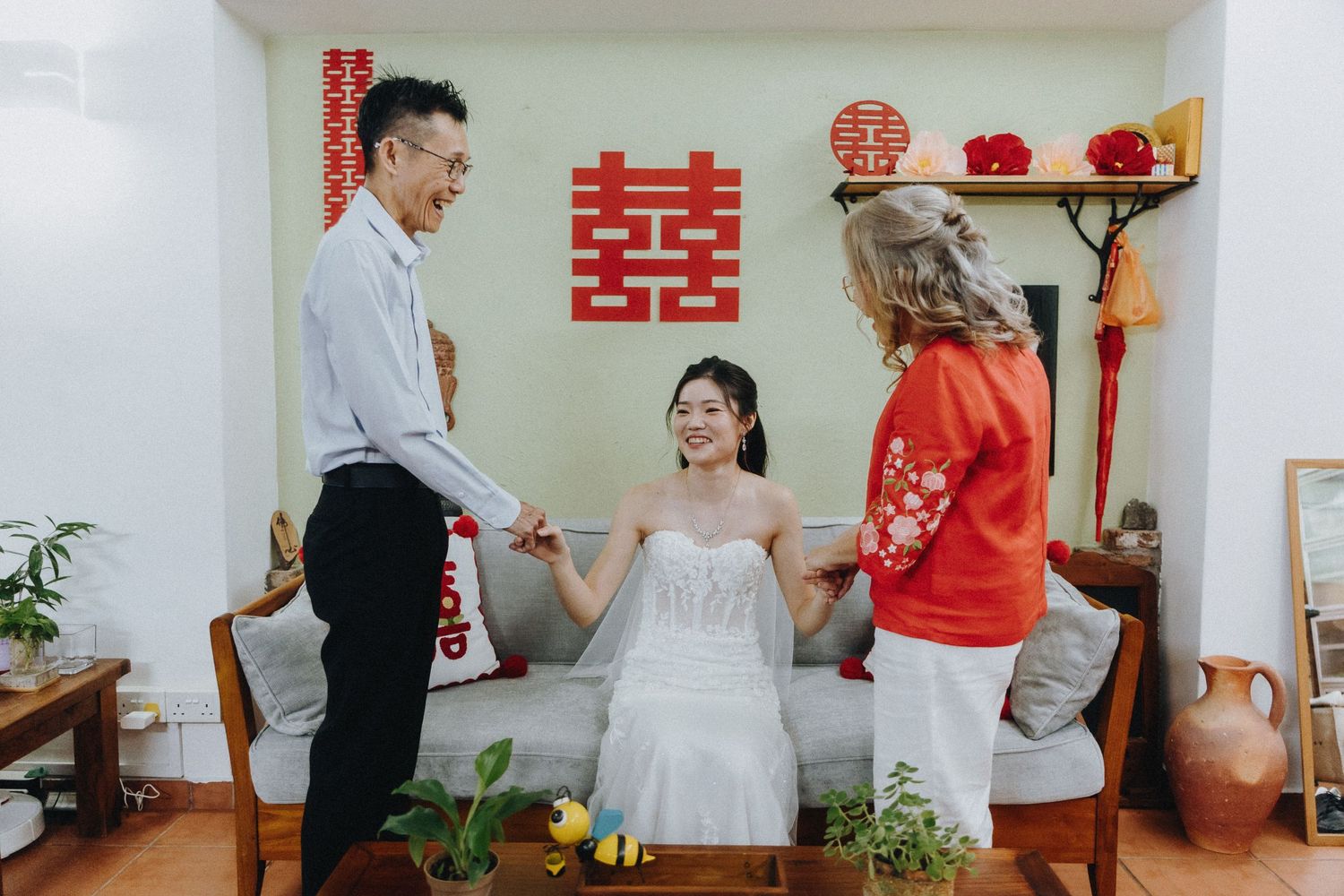 Chinese wedding traditions are observed as a couple participates in a tea ceremony with decorative double happiness symbols.