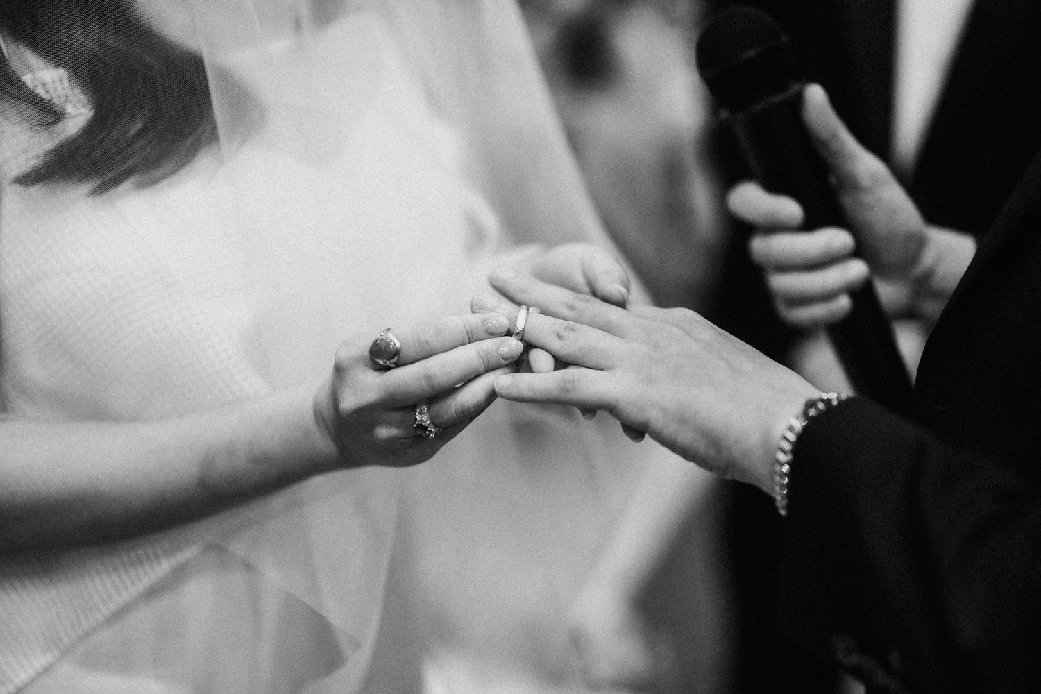 Close-up details of wedding rings and hands during ceremony.