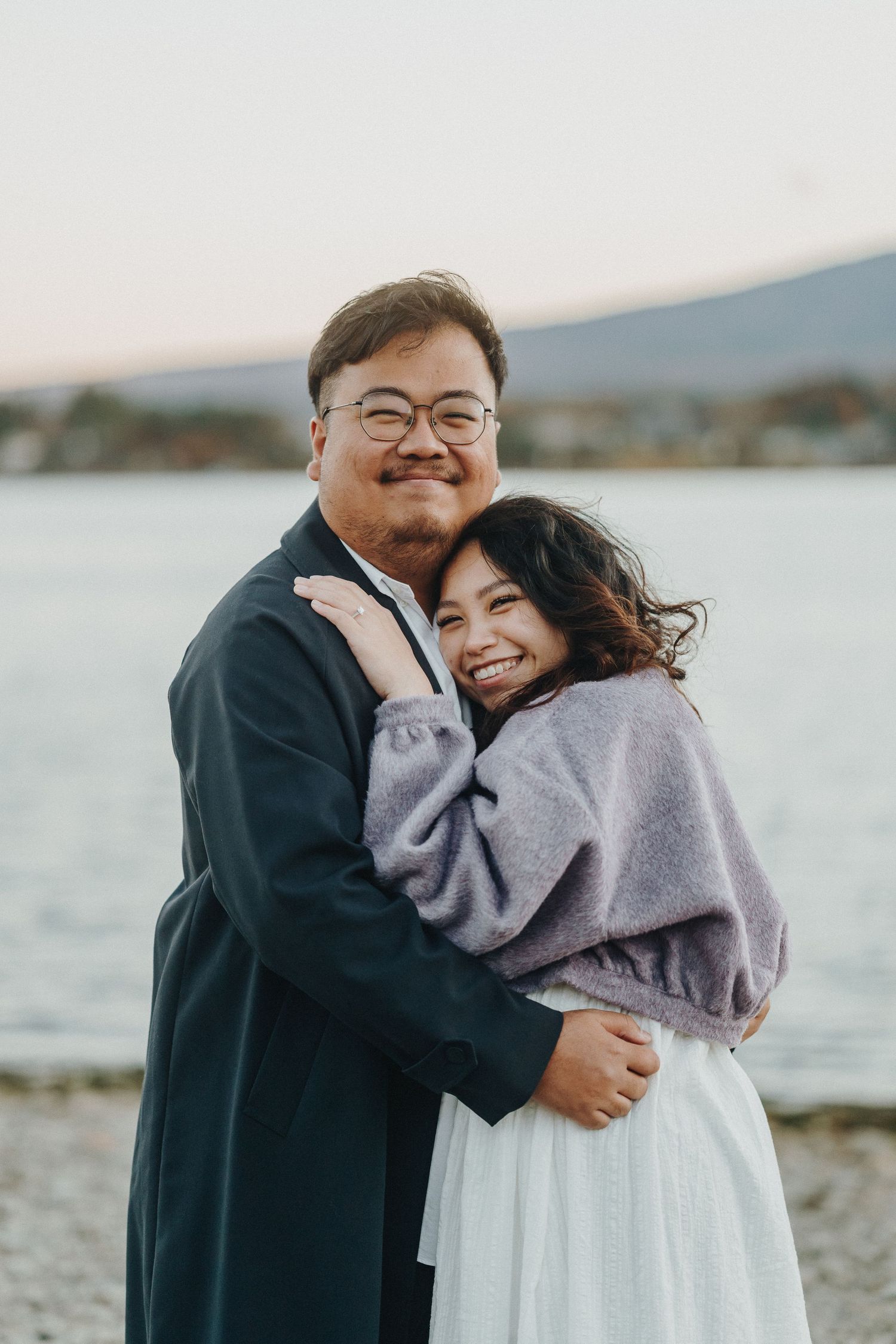 Couple sharing an intimate moment on a rocky beach at dusk.