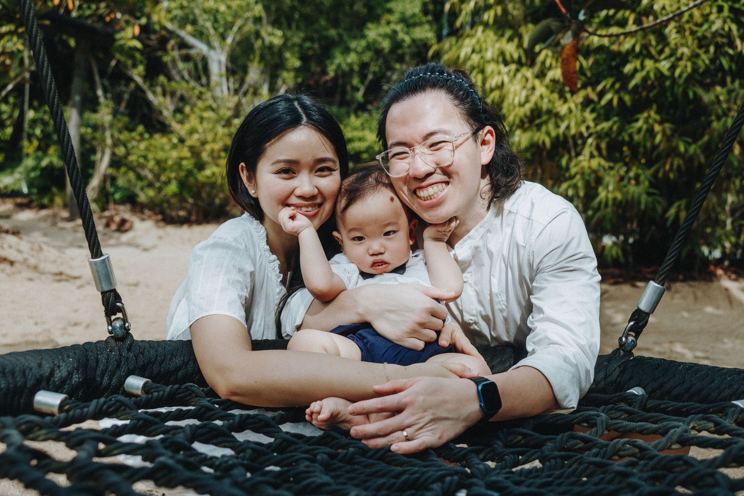 A family enjoying a relaxing moment together while sitting on an outdoor net hammock in a garden setting.