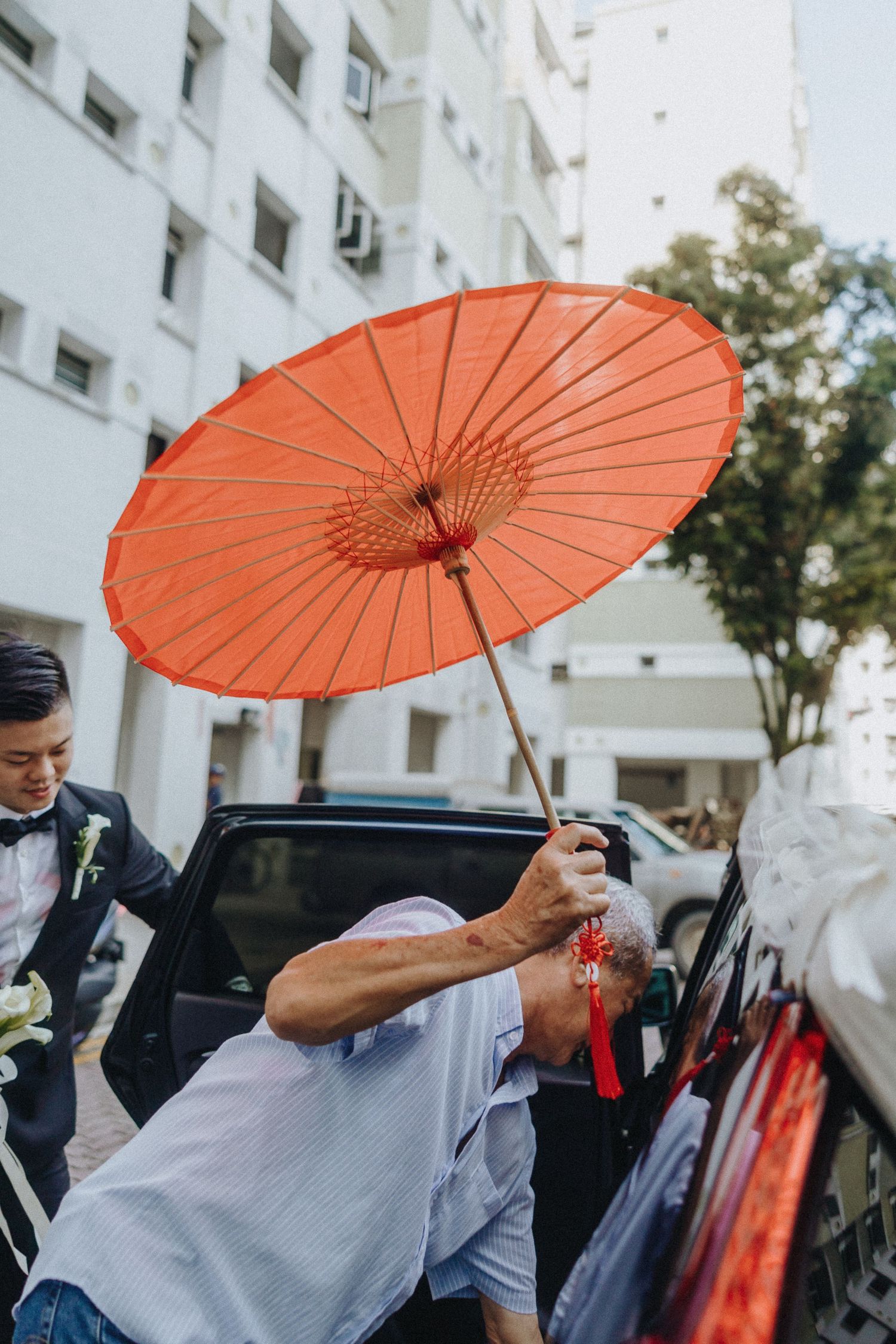 A sequence showing someone holding an orange paper parasol against a bright outdoor backdrop.