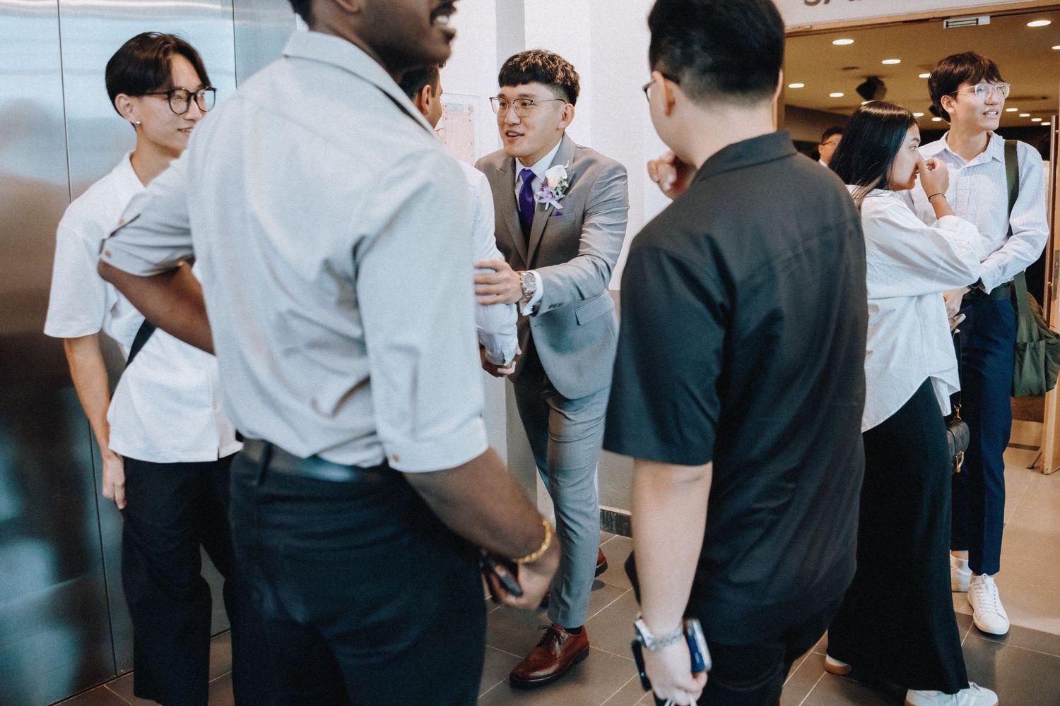 Small group gathered in casual conversation wearing mix of formal and casual attire.