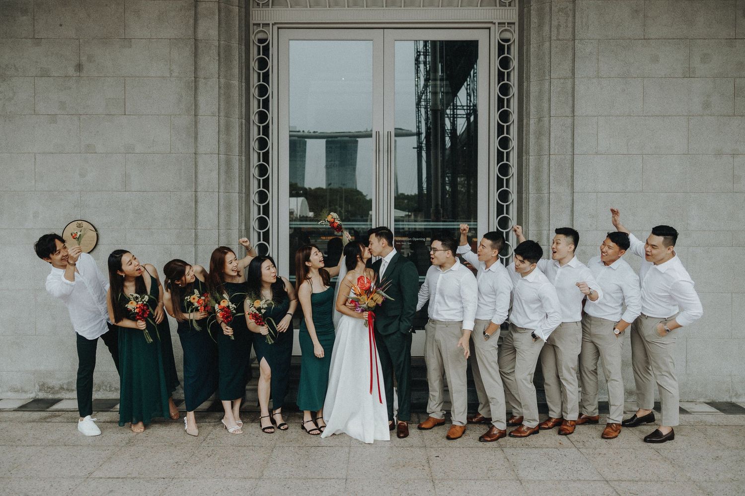 Wedding party posing against a stone wall in formal attire.