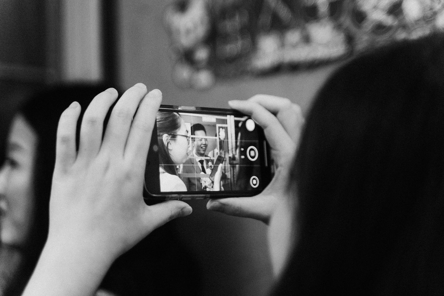 Hand holding smartphone to take photos at an event in black and white photography.