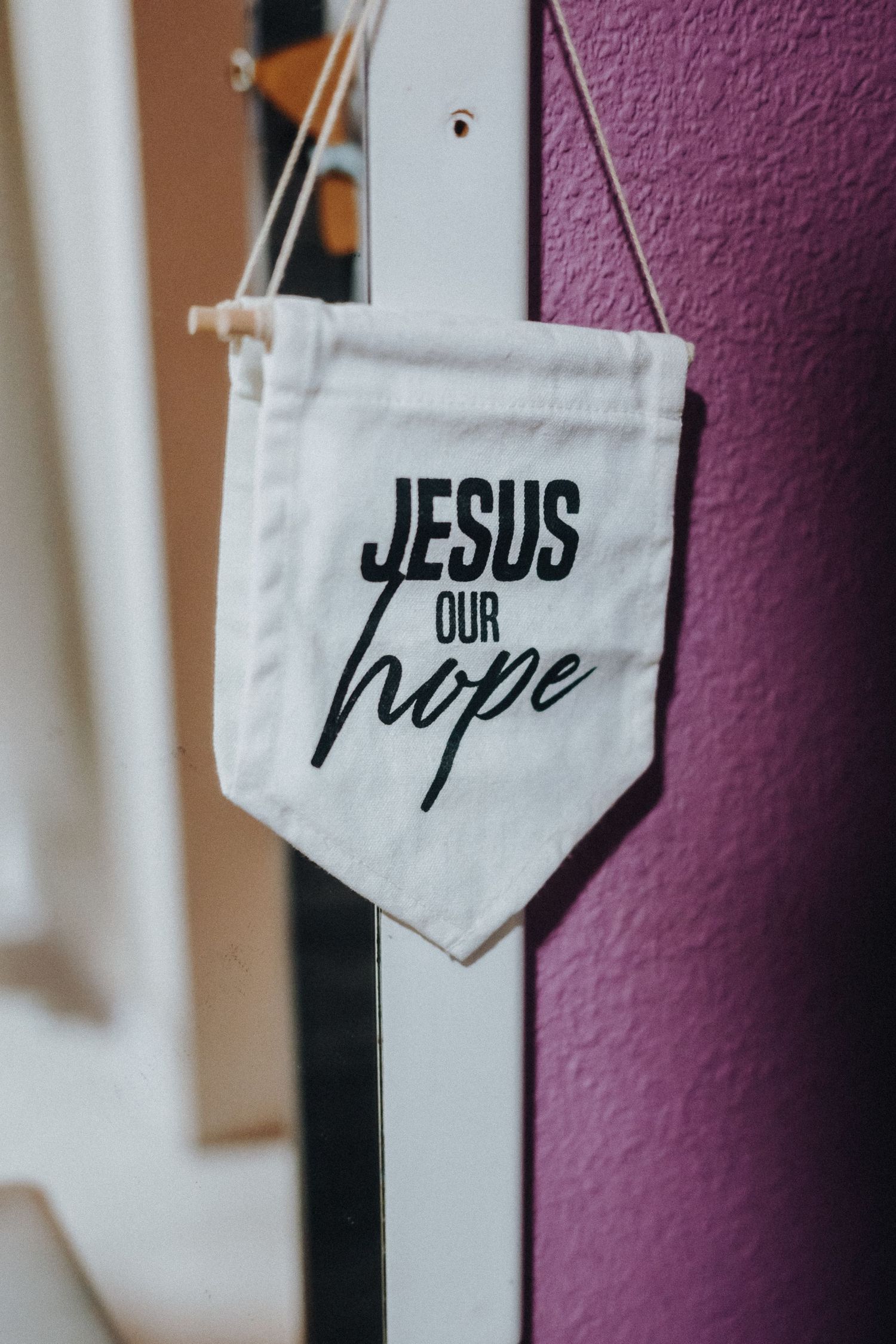 A white fabric banner with black text reading 'JESUS our hope' hangs against a purple wall.