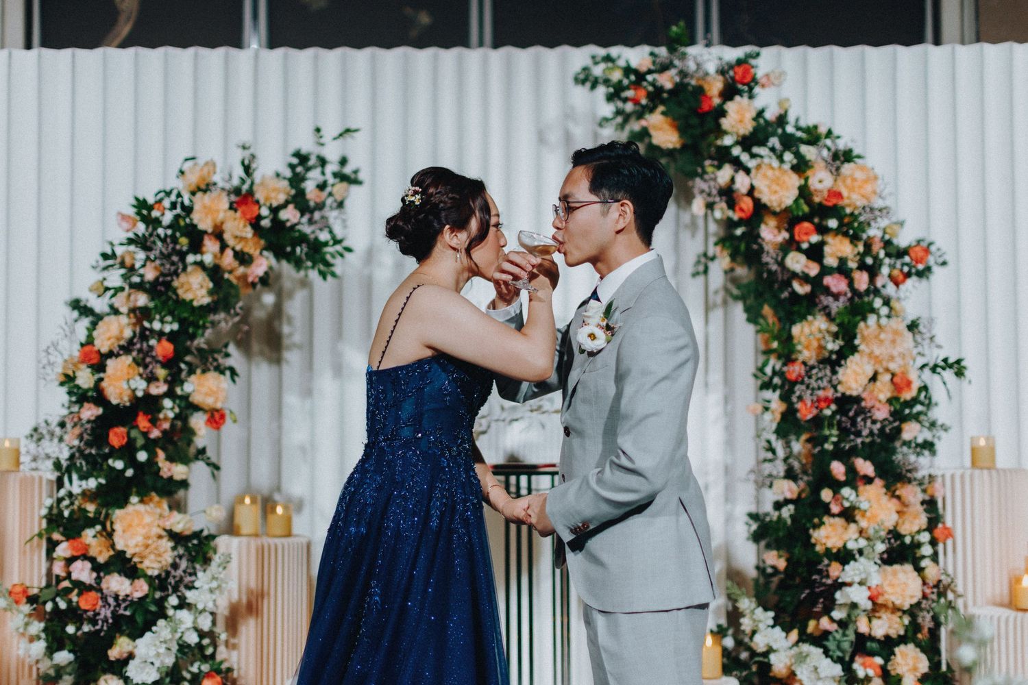 Wedding ceremony setup with peach and coral floral arch arrangements.