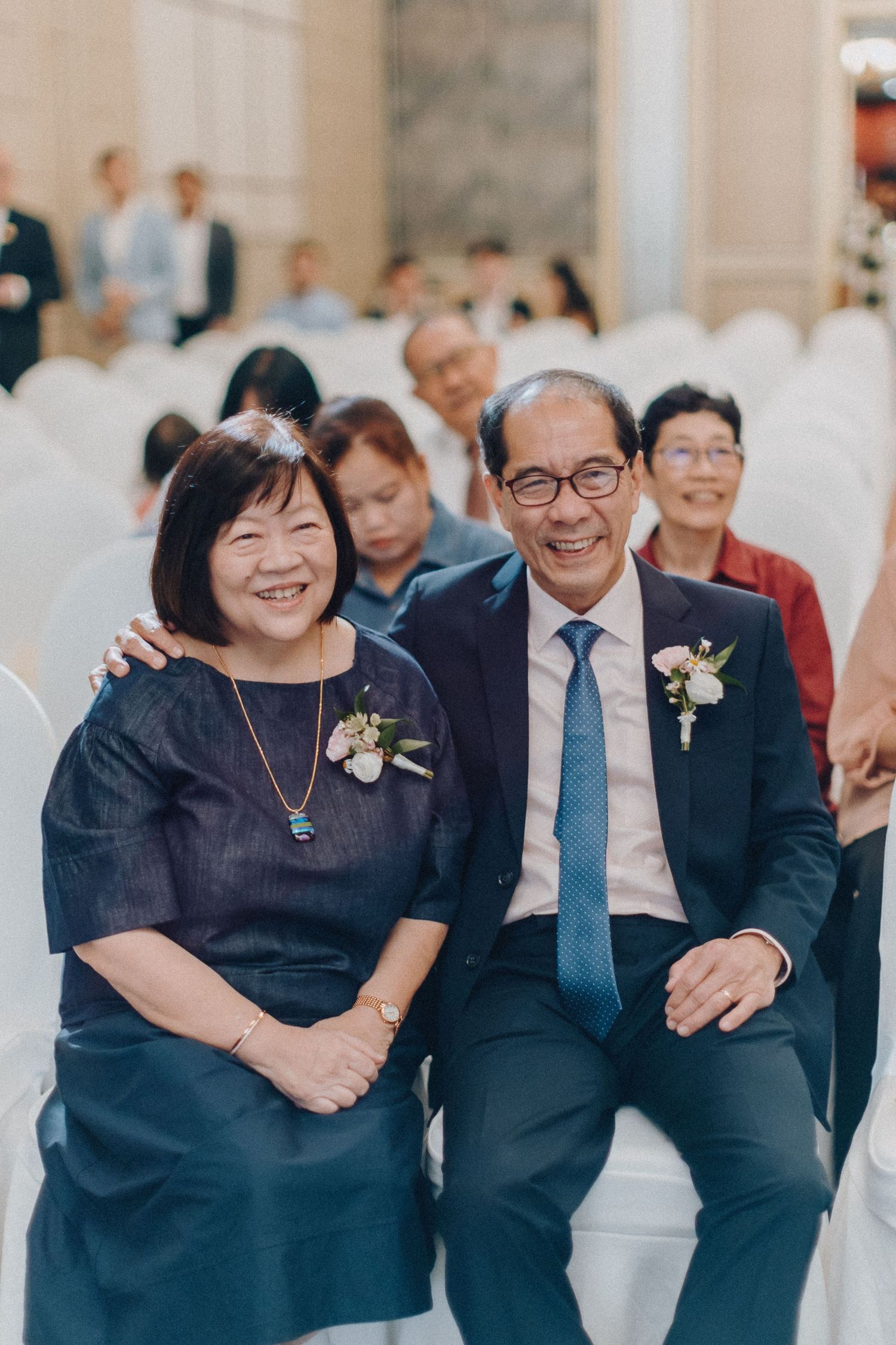 Wedding guests in formal attire share laughs during the celebration.