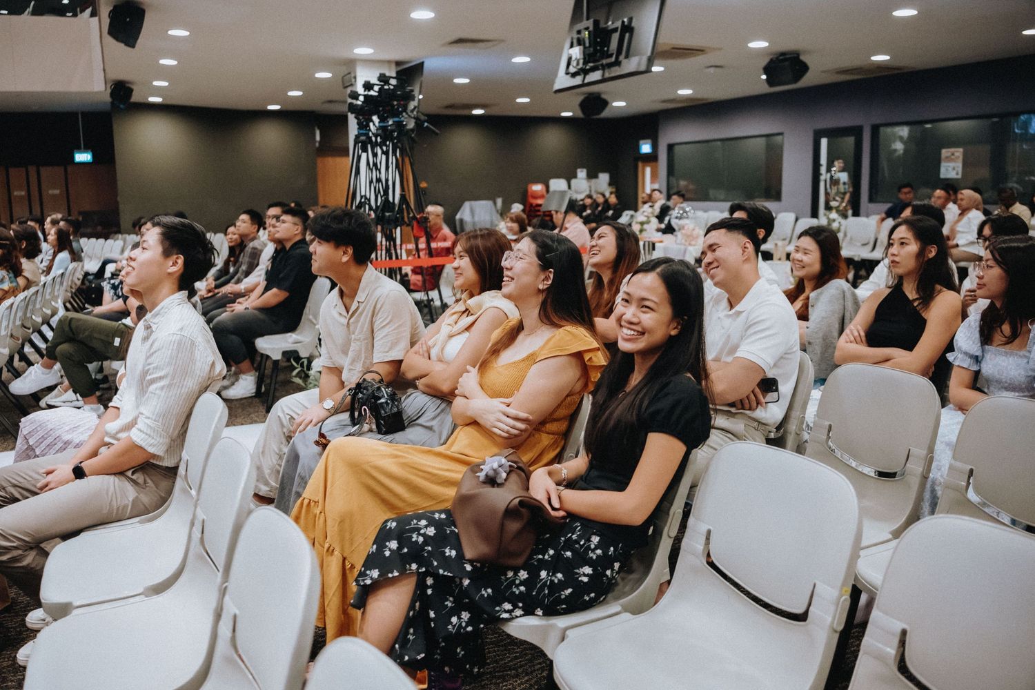 Wedding guests seated in auditorium chairs enjoying ceremony entertainment.