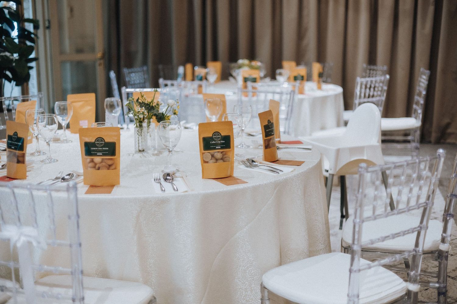 Elegant wedding reception table setup with white linens, crystal chairs, and gold menu cards.