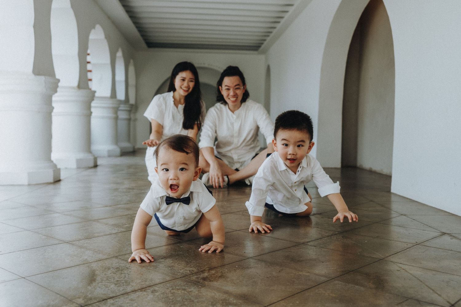 A group of people in white clothing doing pushups in a bright hallway with ornate white columns.