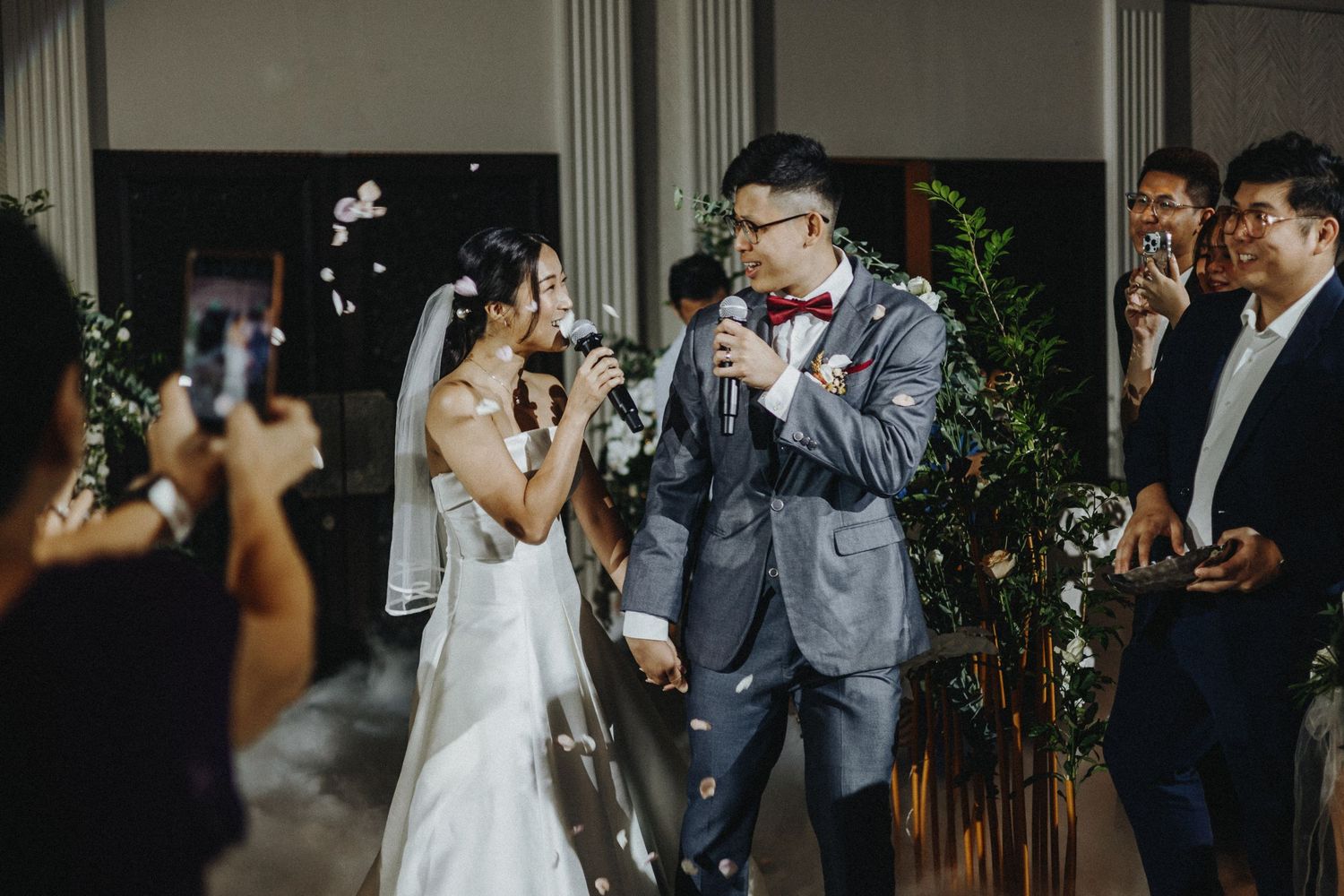 Wedding celebration with guests raising glasses for a toast in an elegant venue.