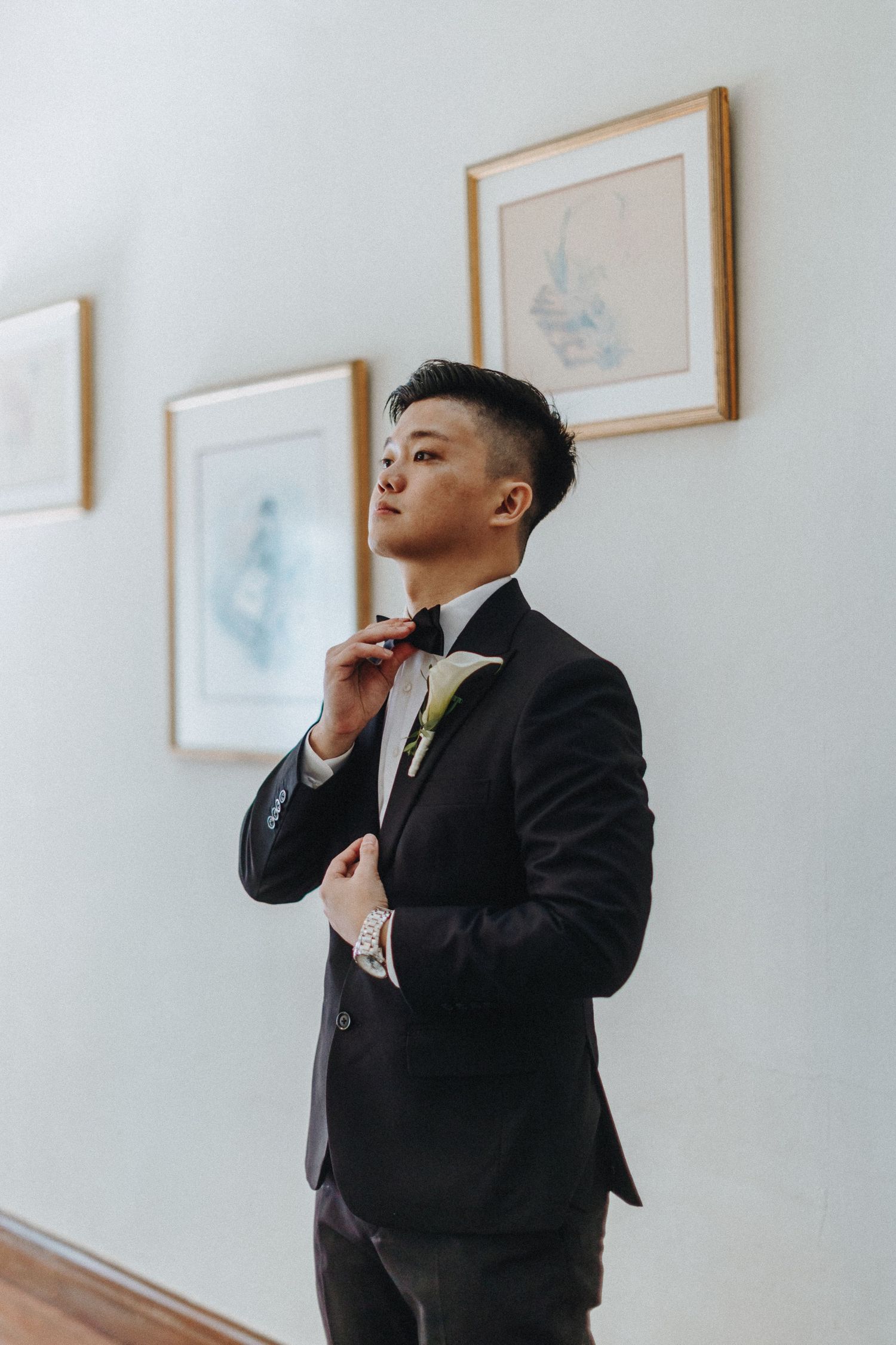 Progressive shots of someone in a black suit posing dramatically against a white wall with framed artwork.