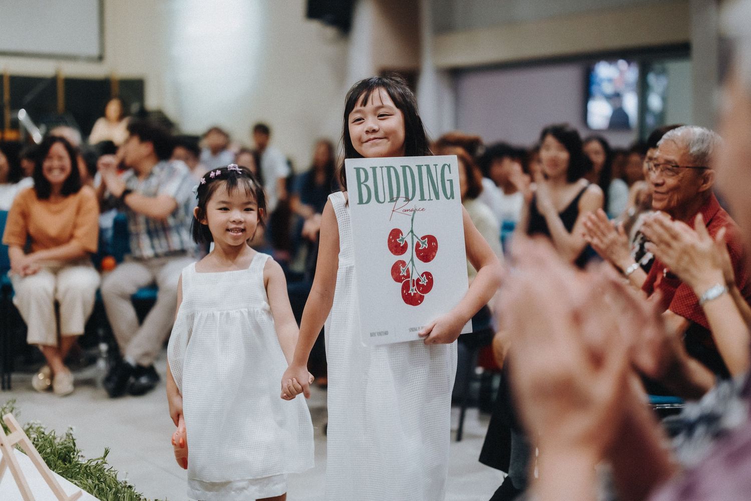 Wedding ceremony guests gathered in a white-themed celebration space.