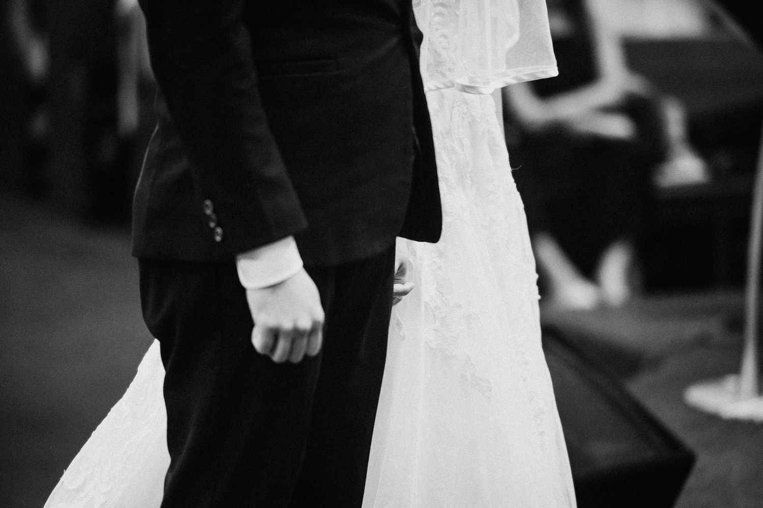 Black and white photograph of a wedding celebration in an indoor venue.