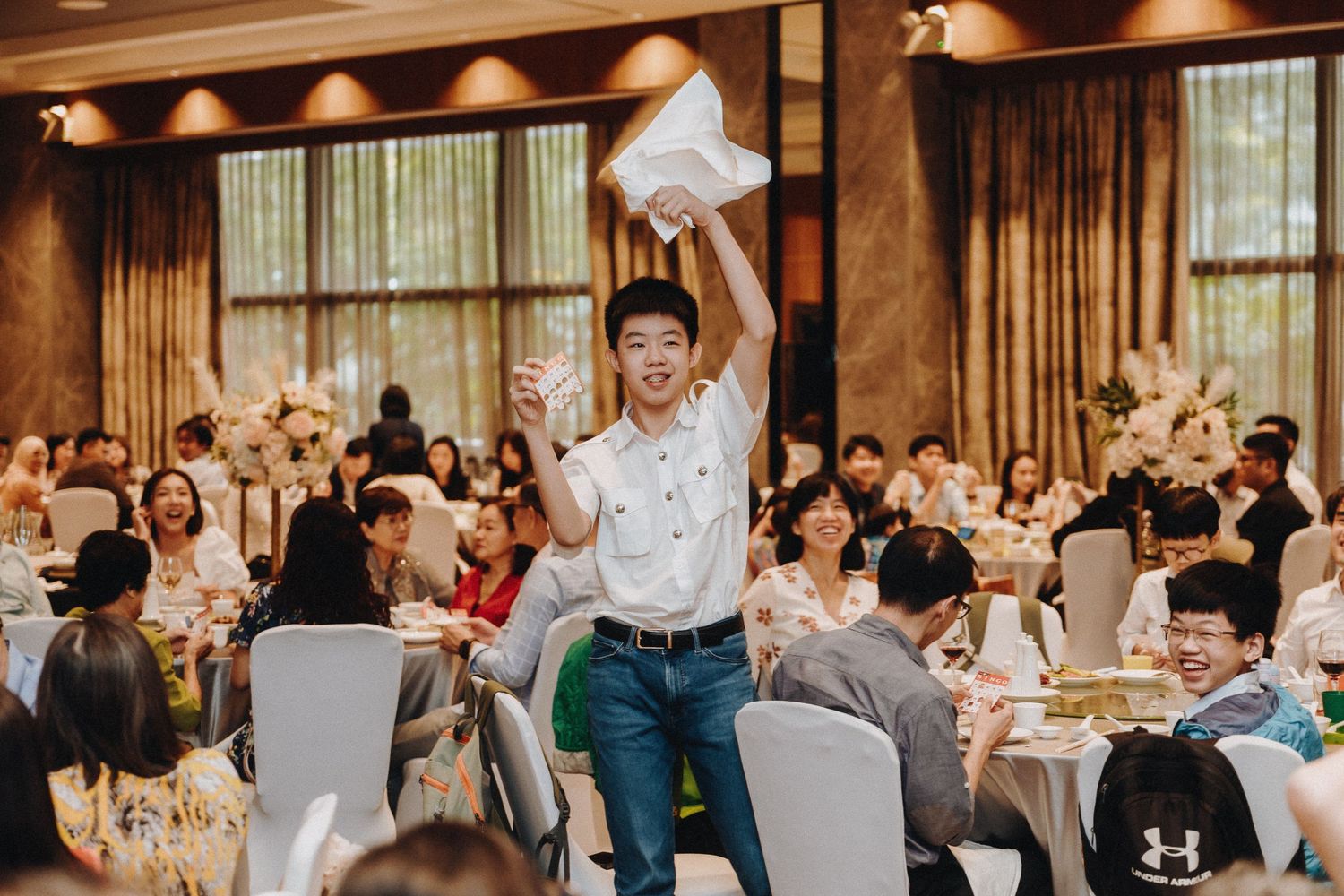 A guest jumps up with excitement during a wedding reception in an elegant banquet hall.