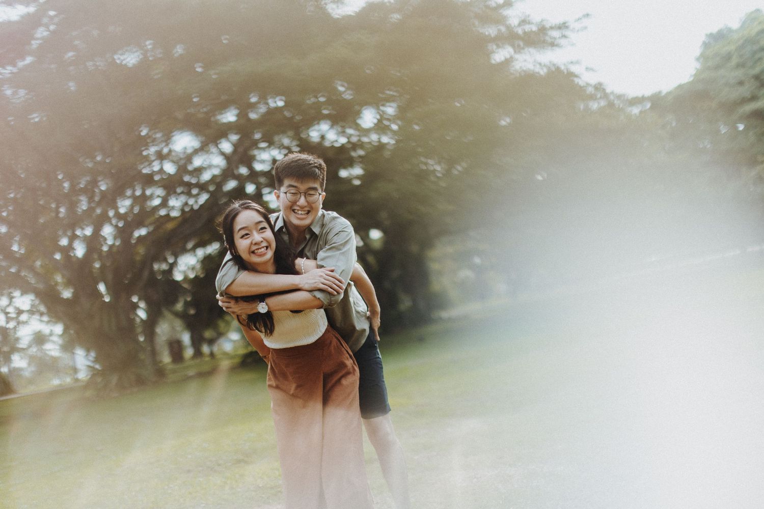 A couple embraces in an ethereal misty forest setting during a romantic photoshoot.